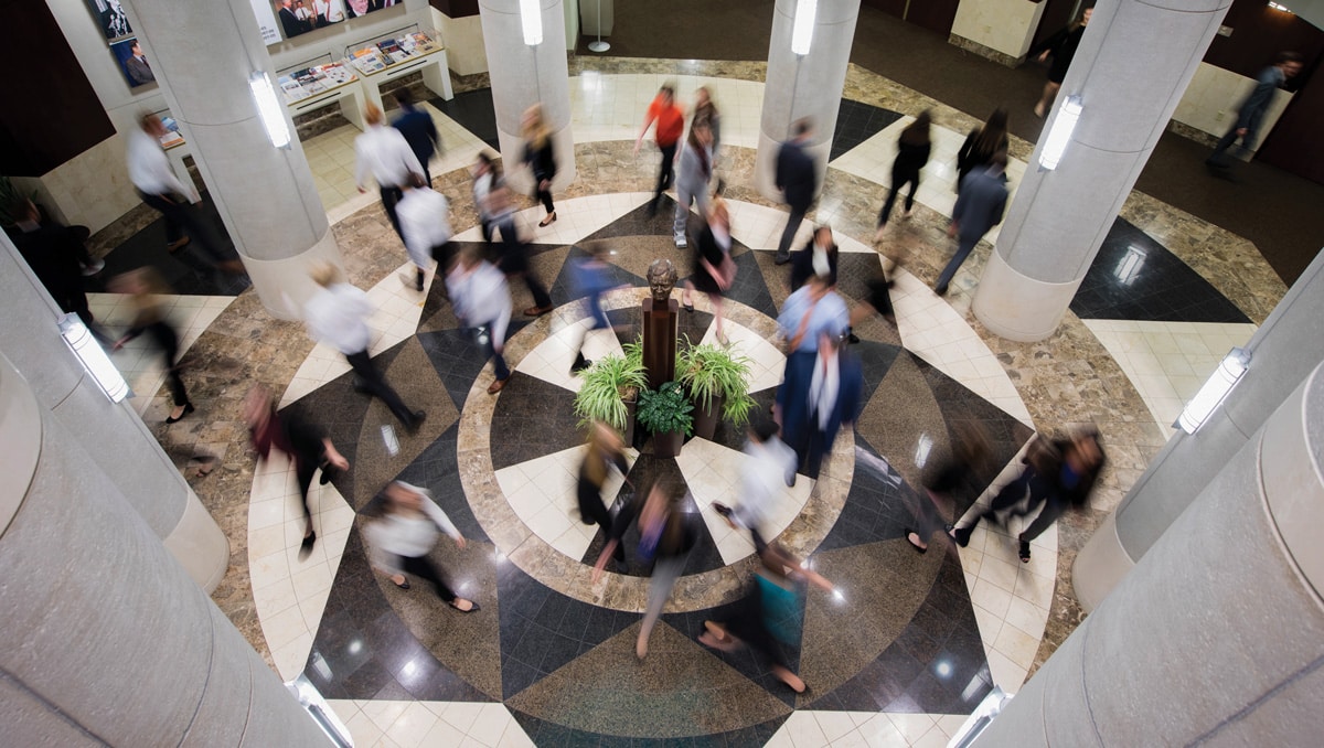 People appear as blurs walking in the lobby of the Baker Center