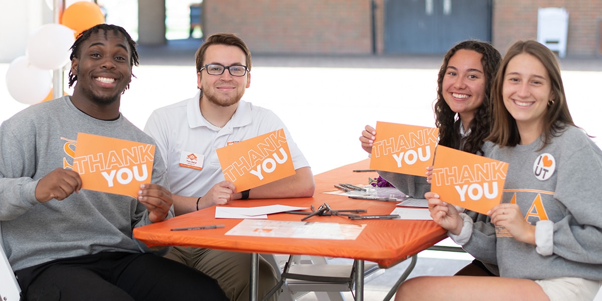 students hold up cards that say thank you