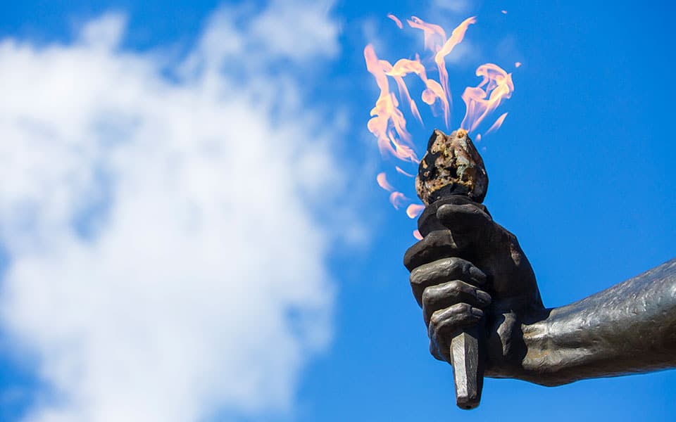 The Torchbearer flame against a blue sky