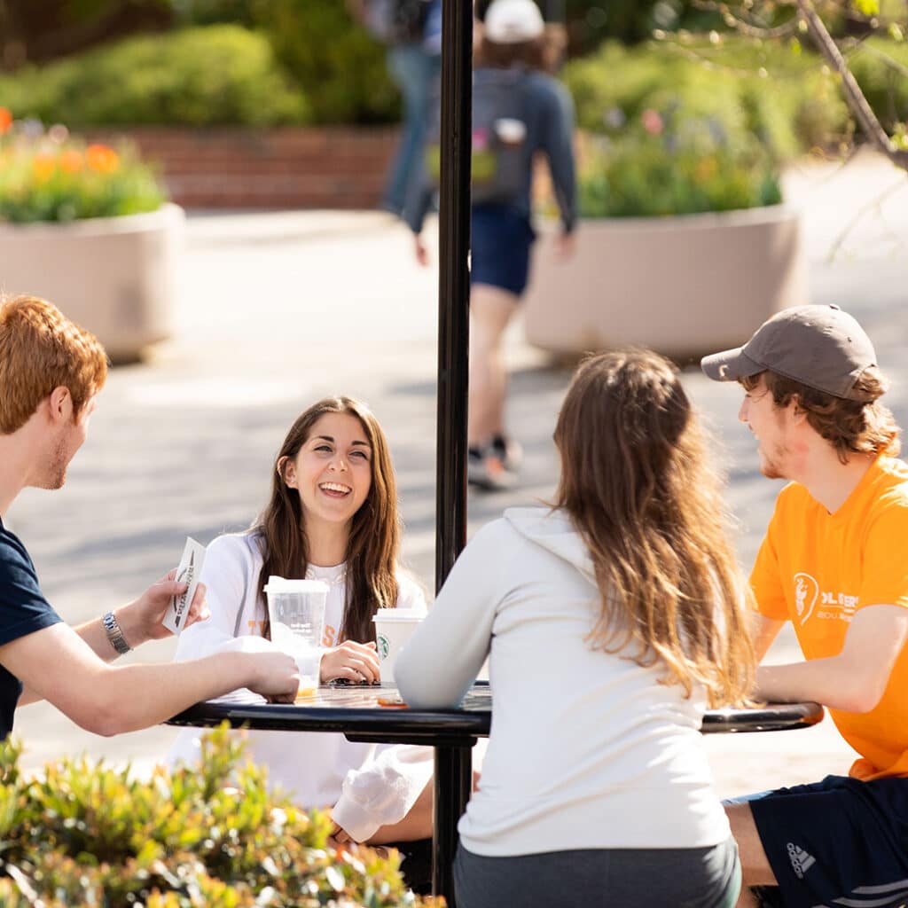 Four students sitting at a table on campus