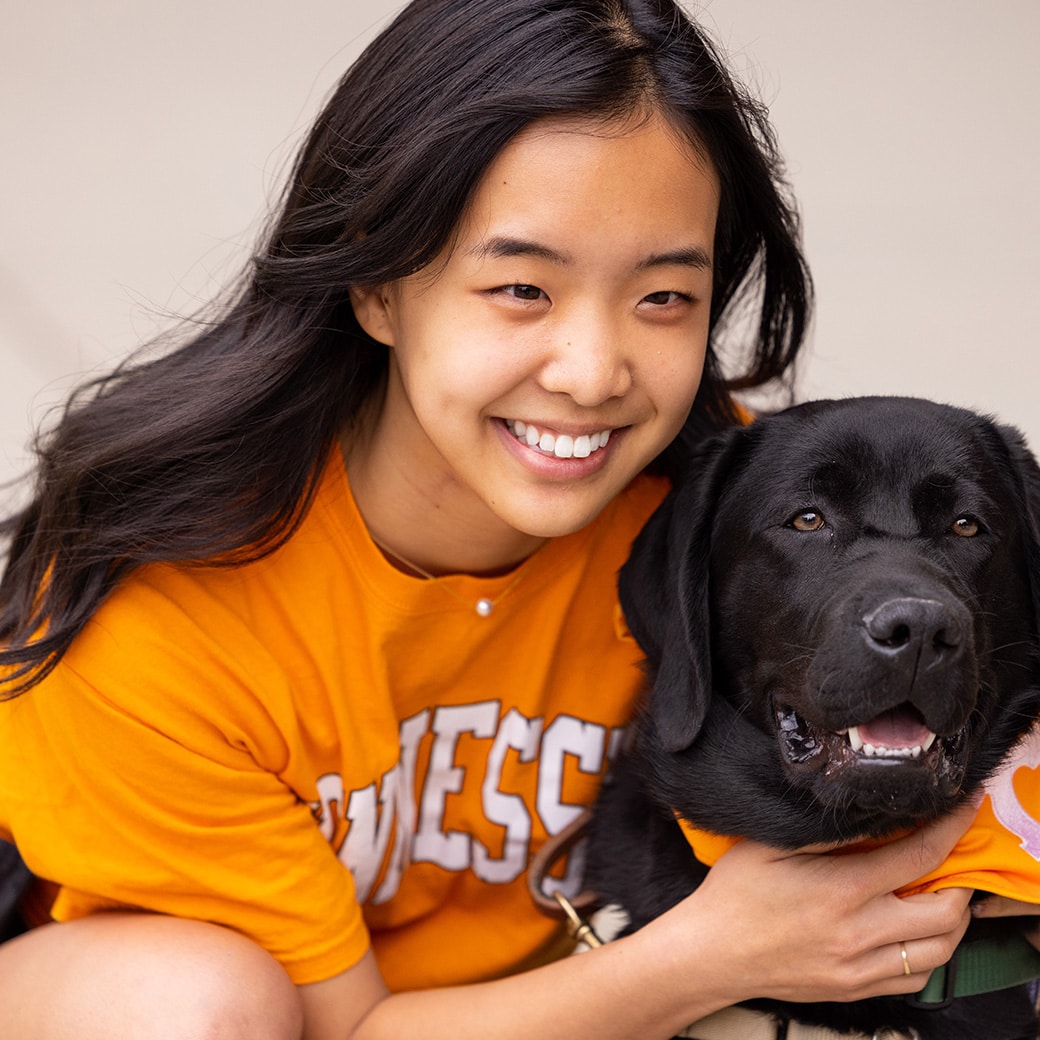 A student poses with a black lab