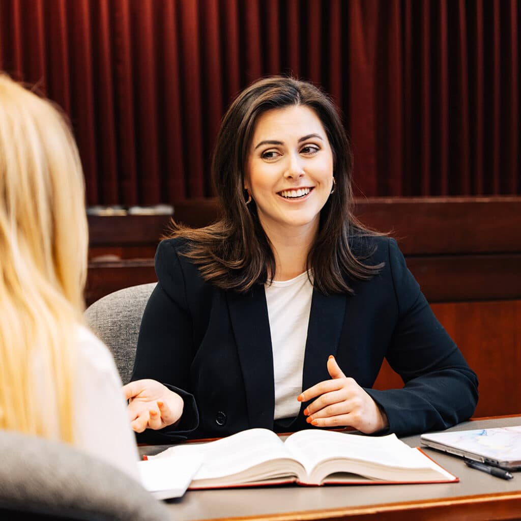 A woman in a suit talks with another woman off-screen