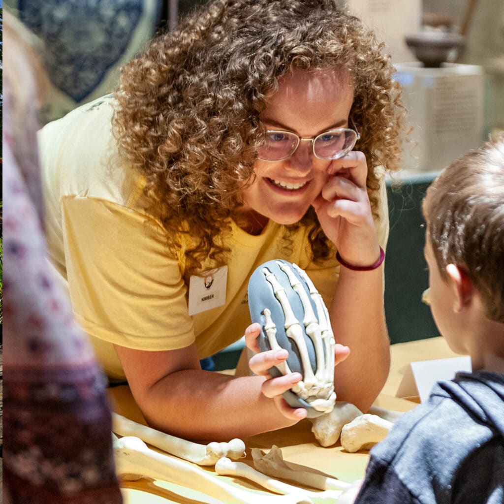 A woman shows a dinosaur skeleton to a young child