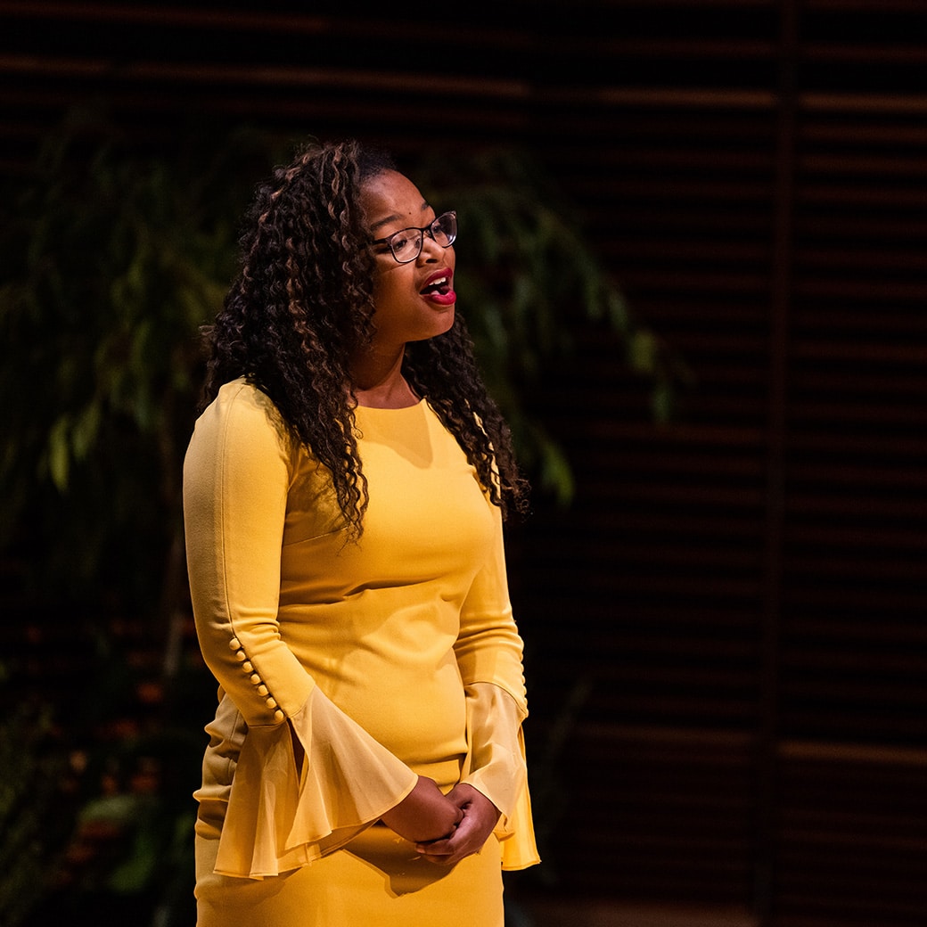 A woman in a yellow dress singing