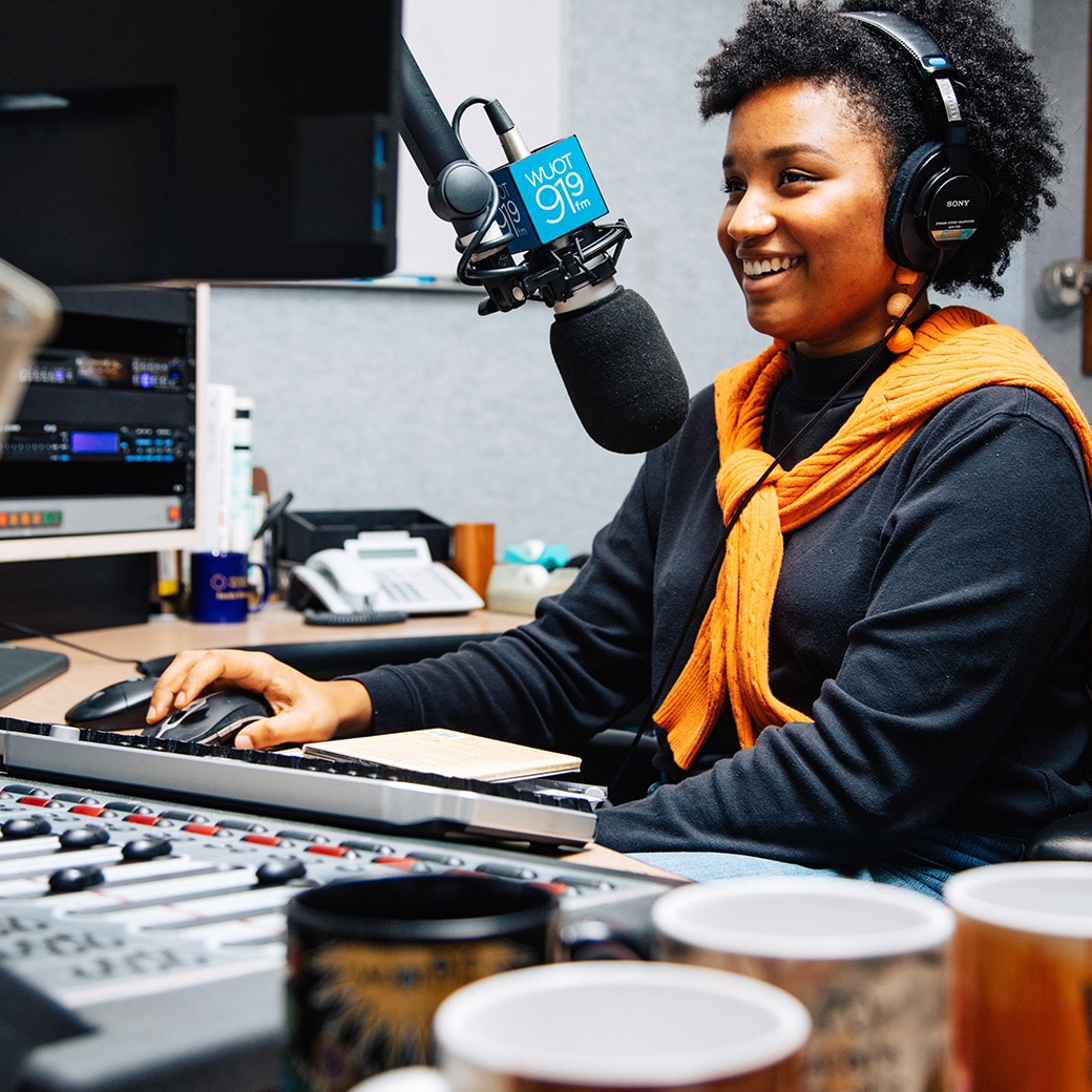 A DJ sits at a microphone