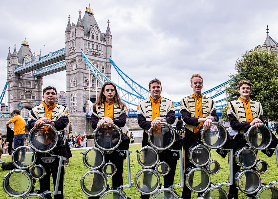 Pride of the Southland Band drummers stand in front of Tower Bridge in London