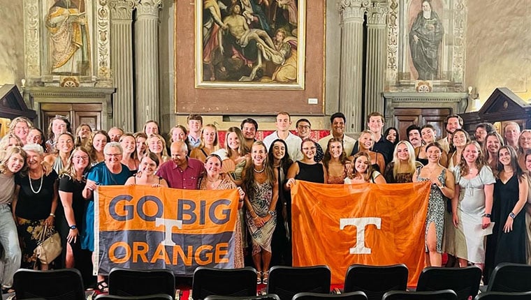 A group of Vols pose with one flag that says Go Big Orange and one flag with the Power T