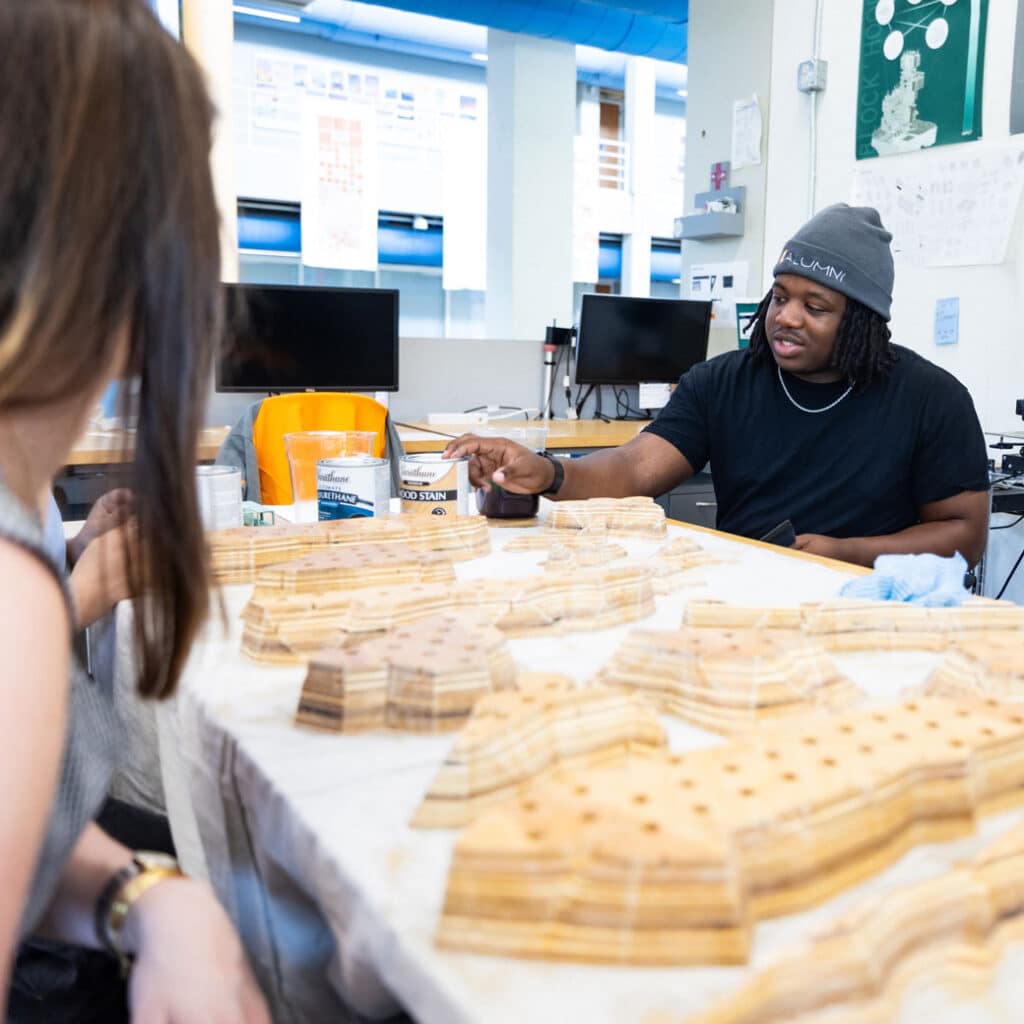A student in a UT Knoxville Alumni hat with wooden model pieces