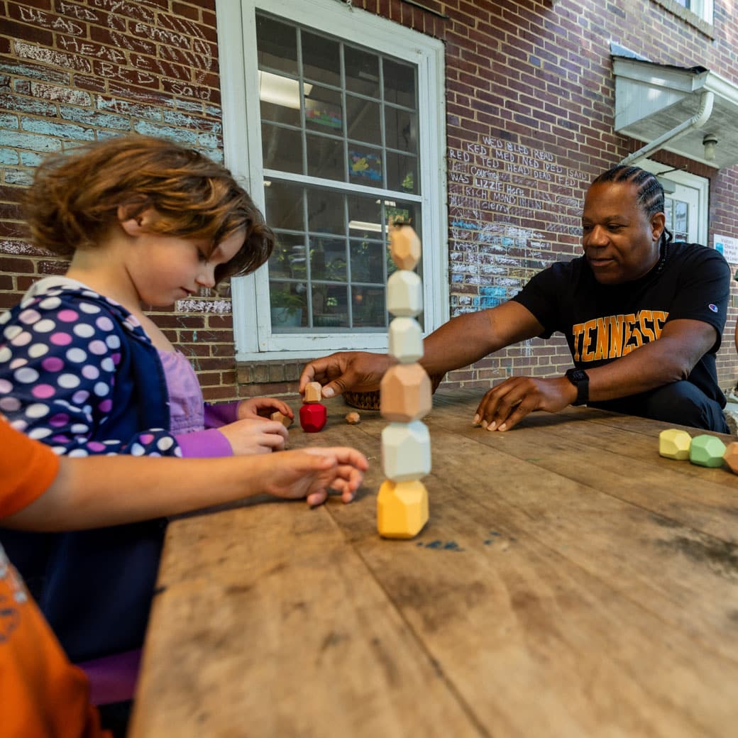 A man helps a young child with blocks
