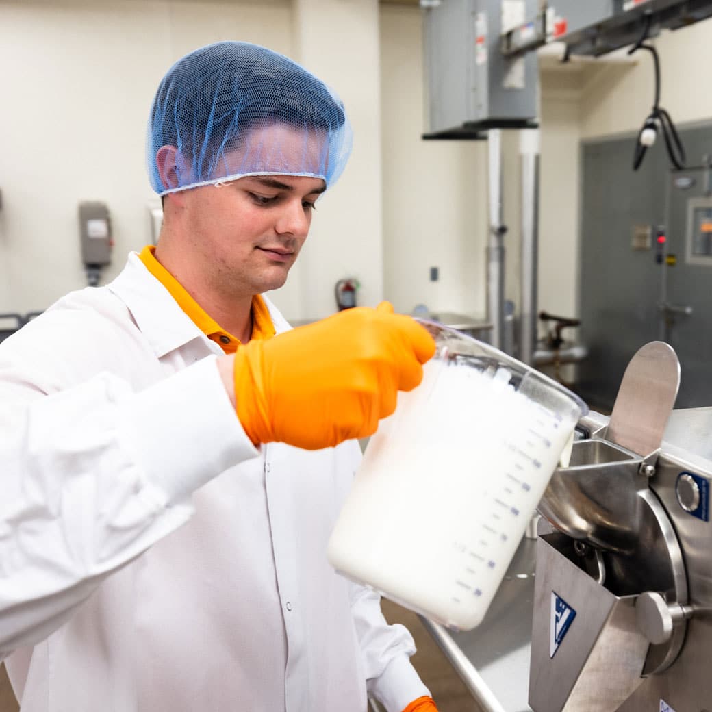 A Food Science student wearing a lab coat and hair net works in the UT Creamery