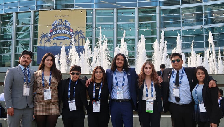 A group of students stand in front of a fountain