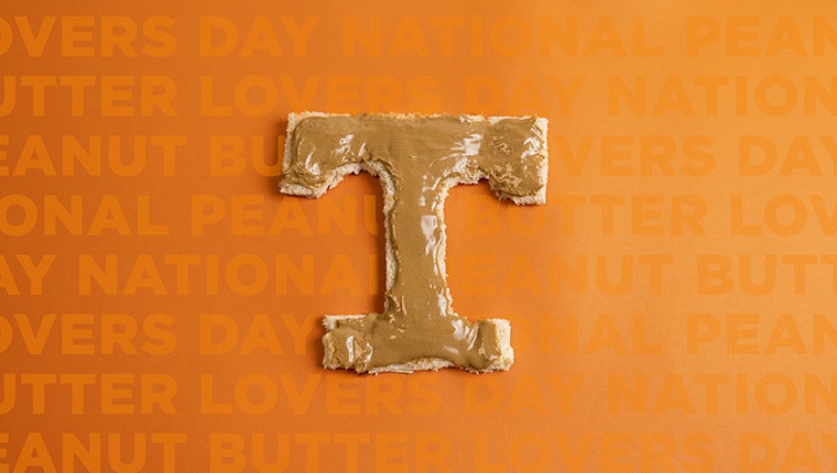 A piece of bread cut into the shape of the Power T, covered in peanut butter, against an orange background that reads National Peanut Butter Lover's Day