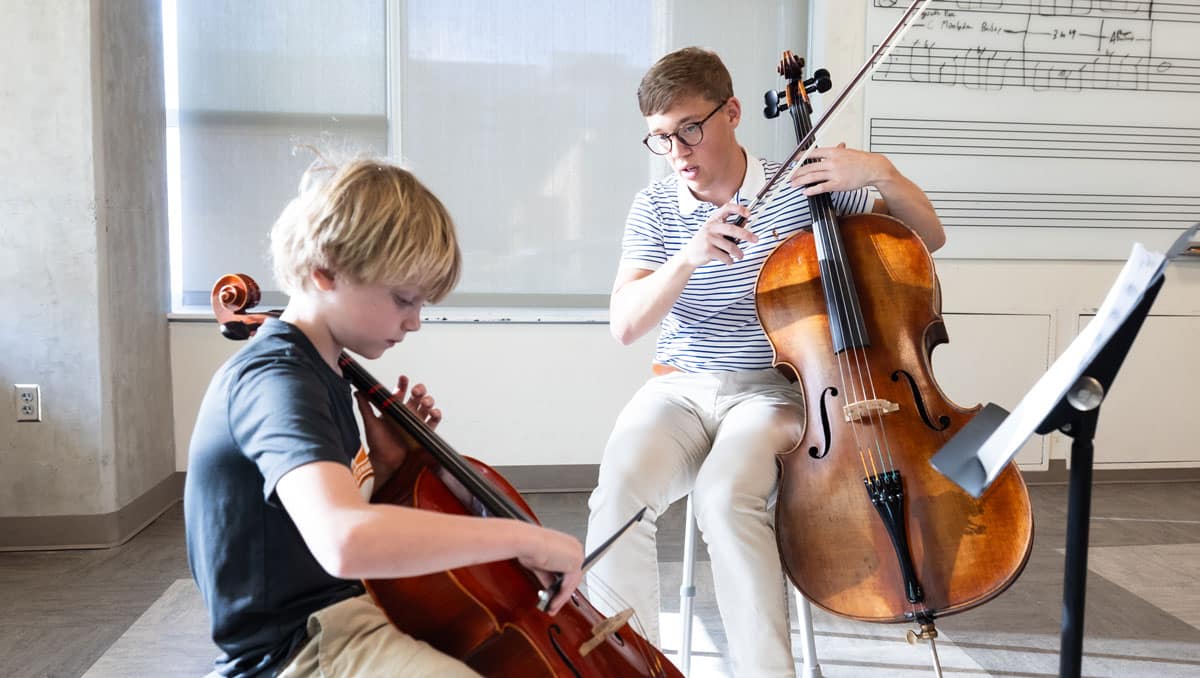 Stephen Arthur showing a young student how to play the cello.