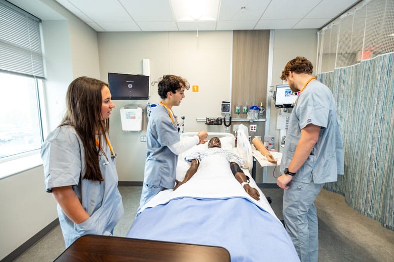 greenberg-oster-jiro-nursing-800x533 Jiro Greenberg-Oster and fellow nursing students in the simulation lab with a manikin.
