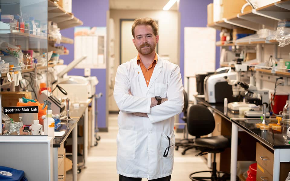 myers-tyler-960x600 Tyler Myers, in a white lab coat, stands with his arms crossed in the Goodrich-Blair Lab.