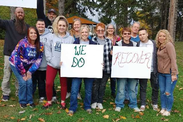 we-do-recover-768x512 A group of people stand together, holding signs that say We Do Recover in Huron County"