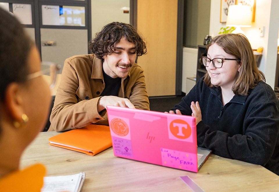 Two students look at a laptop screen.