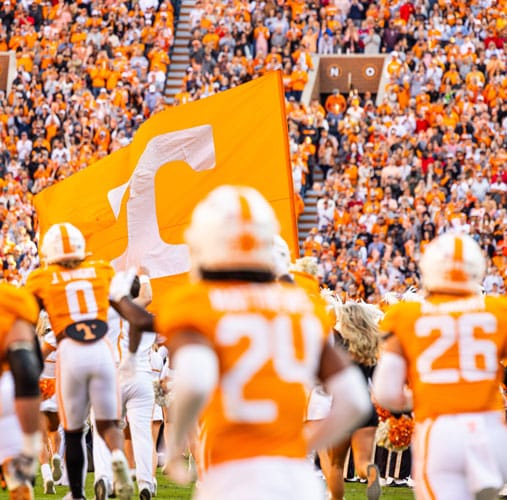 fye-2025-gallery-athletics Tennessee football players enter the field at Neyland Stadium. In the background are cheering fans.