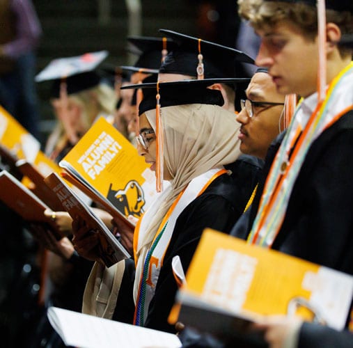 Fall Undergrad Graduation SB Graduates looking at their commencement programs.