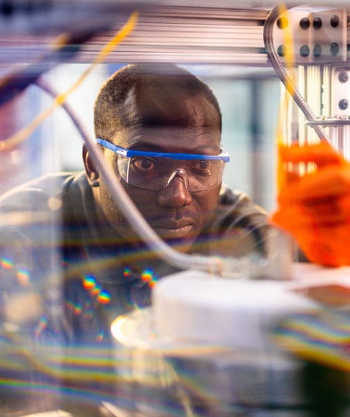 A student wearing safety goggles and gloves works in the Bioenergy Fuel Lab.