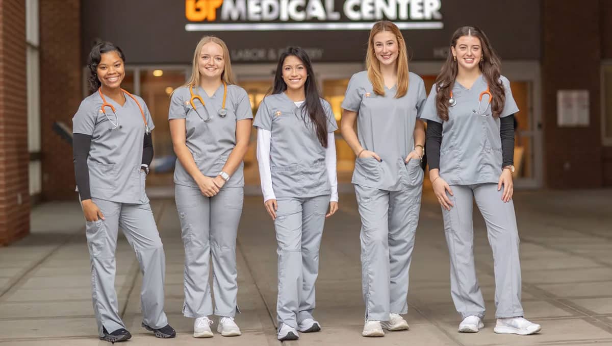 Five nurses, Jordan Ballenger, Marcella Bertke, Maggie Comer, Lauren Denney, Camille Charvet, stand in front of UT Medical Center.