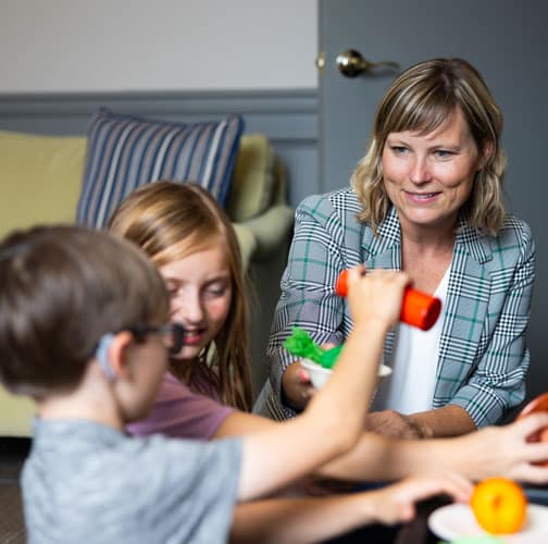 A woman works with two young children.