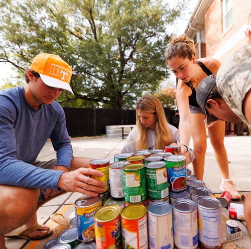 Students stack cans in a tower formation.