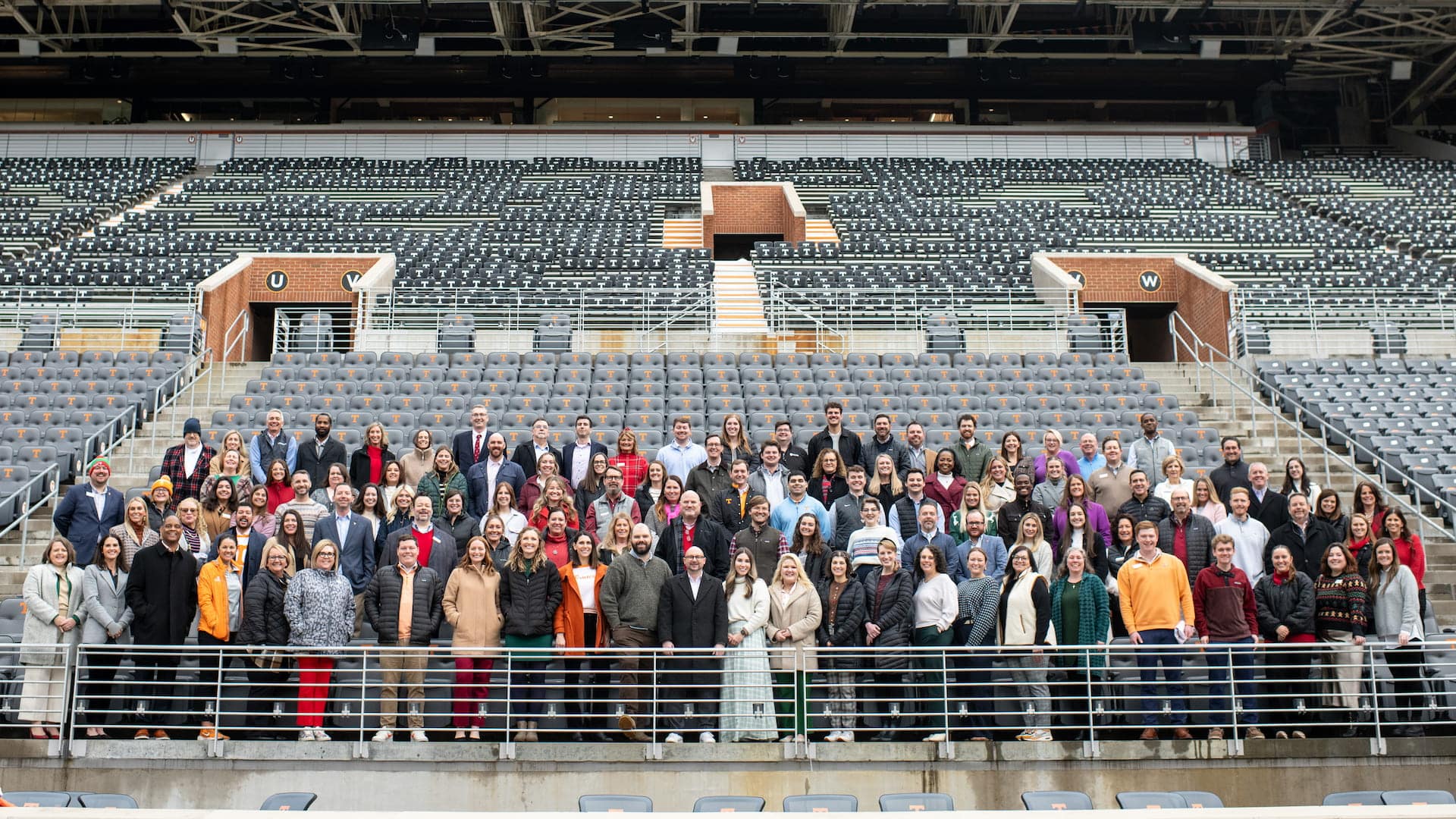 55025545264_81f18b791f_o (1) people in a football stadium section smiling for a group photo