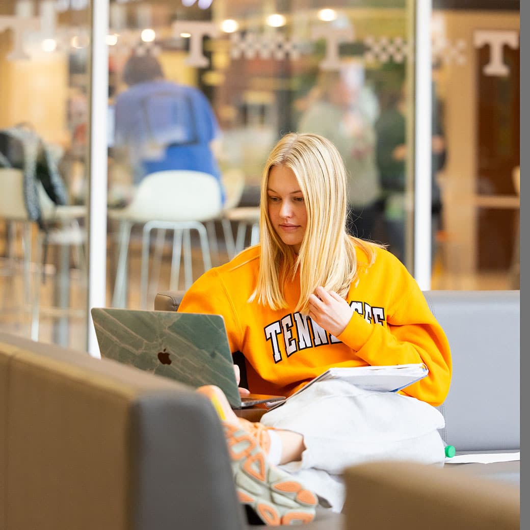 Person in UT orange shirt starting at computer on campus
