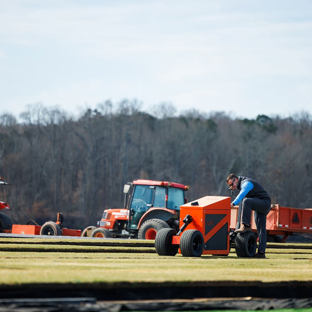 Person in field working on grass with a machine