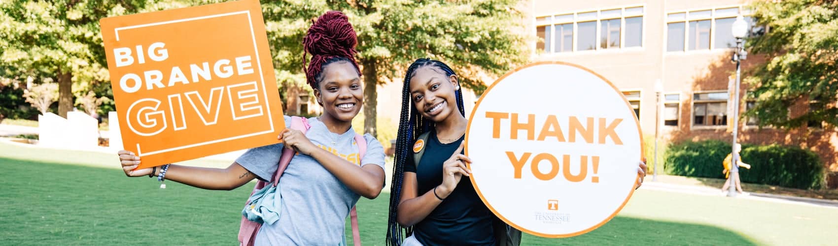 Students hold signs that say Big Orange Give and Thank You